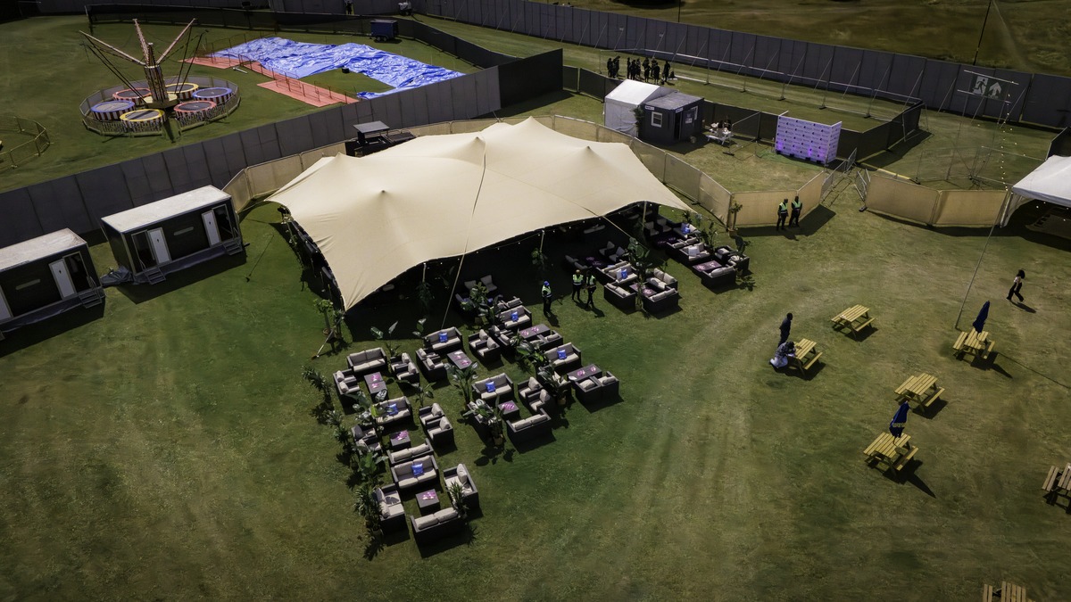 Stretch tent structures going up across an open festival site
